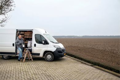Jan Wubs bij zijn werkbus in de weidse vlakte van Luttelgeest